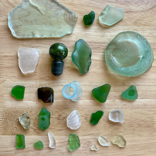 Collection of green and clear glass pieces on a wooden surface
