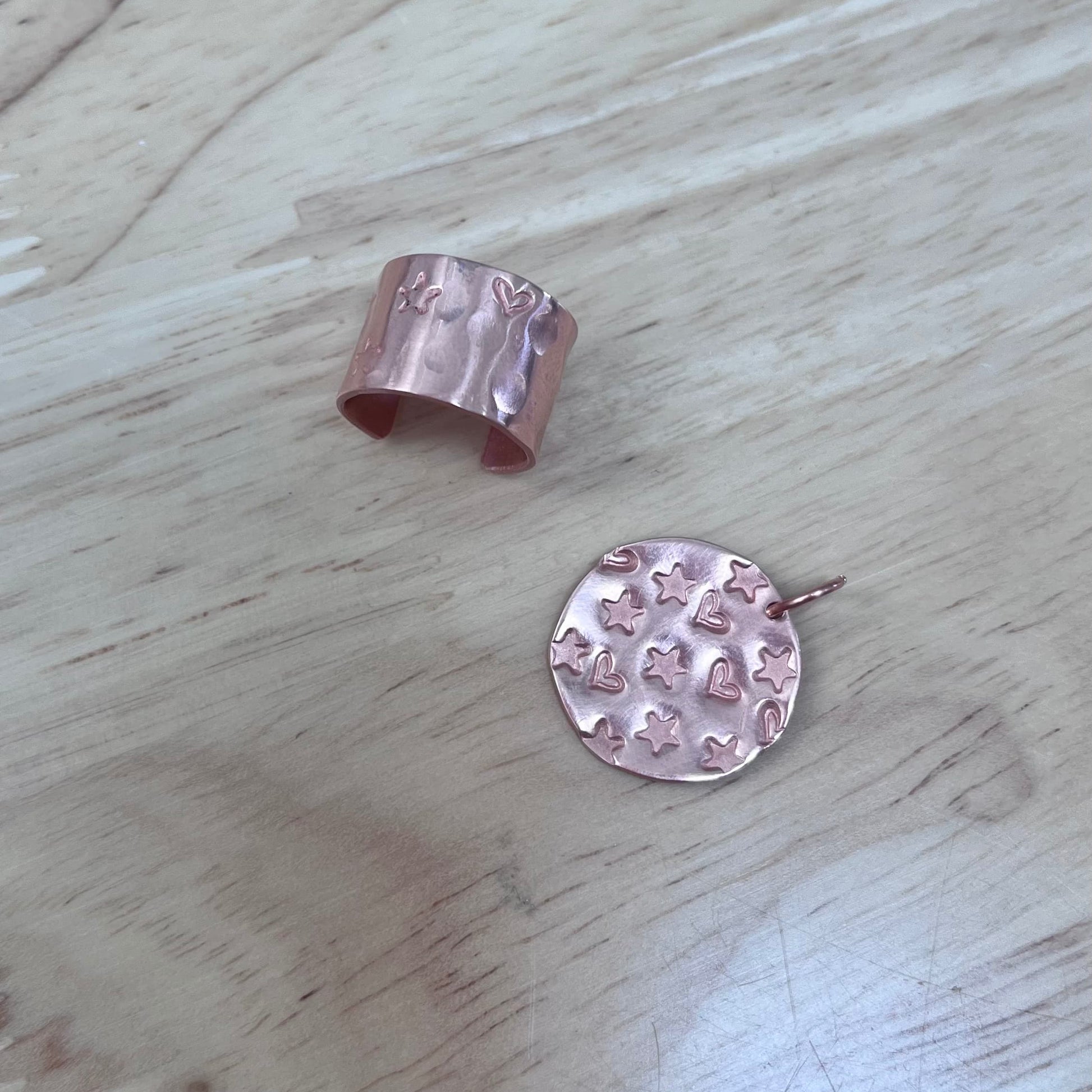 Two pieces of copper jewelry on a light wooden surface